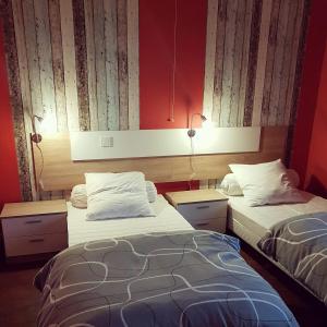 - 2 lits dans une chambre aux murs rouges dans l'établissement Gite La maison d'Odette, à Saint-Georges-de-Mons