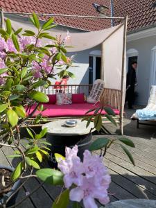 a porch with a couch on a deck with pink flowers at feels Beach Club Hotel in Kühlungsborn