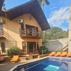 une maison avec une piscine et un balcon dans l'établissement Chalé Penedo RJ - Centro, à Penedo
