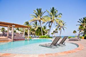 basen z krzesłami i palmami oraz ocean w obiekcie La Perla del Caribe - Villa Sapphire w mieście San Pedro