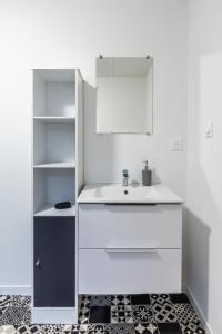 een witte badkamer met een wastafel en een spiegel bij Le 18-GregIMMO-Appart'Hôtel in Bavilliers