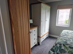 a bedroom with a bed and a dresser and a cabinet at Derwen 2 Bedroom Luxury Lodge in Welshpool