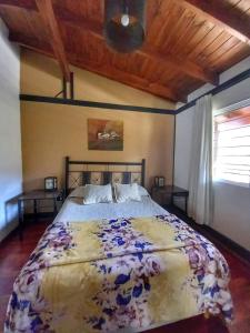 1 dormitorio con 1 cama grande con colcha de flores en Cabañas San Lorenzo en San Lorenzo