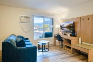 a living room with a blue couch and a desk at Harrison Grand Motel in Harrison Hot Springs
