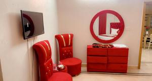Habitación con silla roja, tocador y espejo. en Galaxy Lodge en Islamabad