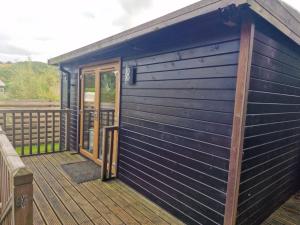 a blue building with a door on a deck at Glamping Hut - Riverside 1 in Welshpool