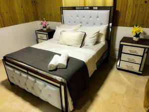 1 dormitorio con 1 cama blanca grande y 2 mesitas de noche en Alaia Casa de campo By Hospedify Para 4 personas, cerca del Río, Naturaleza, BBQ y terraza familiar, en Jarabacoa