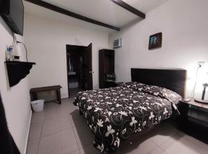 a bedroom with a bed with a black and white blanket at FINCA QUINTA LOS CEDROS in Xilitla