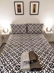 ein Schlafzimmer mit einem schwarzen und weißen Bett mit Handtüchern darauf in der Unterkunft Tranquilo apartamento de dos dormitorios en pleno centro in Plasencia