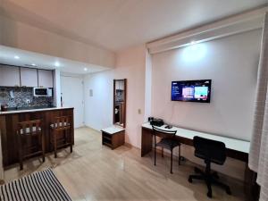 Una sala de estar con un escritorio y un televisor en la pared. en Qi Ibirapuera Intelligence Flat internet fibra e limpeza UH1903, en São Paulo