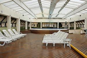 Habitación grande con sillas blancas y piscina en Qi Ibirapuera Intelligence Flat internet fibra e limpeza UH1903, en São Paulo