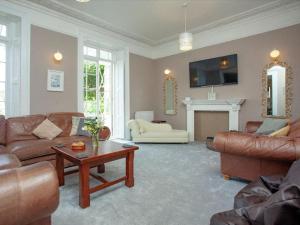 a living room with leather furniture and a fireplace at Glenthorne Villa Torquay in Torquay