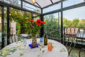 un tavolo con un vaso con fiori rossi sopra di Angelo Raffaele incantevole casa per 12 persone a Venezia