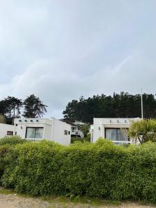 a couple of white buildings with trees in the background at Cabañas Lomas de Pinares in Pichilemu