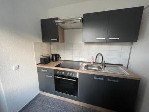 eine kleine Küche mit schwarzen Schränken und einem Waschbecken in der Unterkunft Ferienwohnung - Gästewohnung in Forst(Lausitz) in Forst