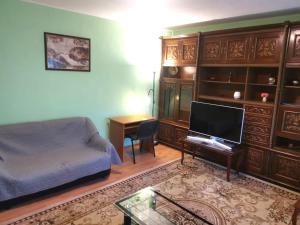 een woonkamer met een bank en een bureau met een televisie bij Central Apartment Bucharest Mall in Vitan