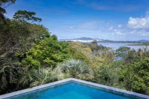 uma piscina com vista para a água e as árvores em Pousada Paraíso do Luz em Barra de Ibiraquera