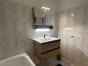 ein Badezimmer mit einem Waschbecken, einer Badewanne und einem Spiegel in der Unterkunft Ferienwohnung - Gästewohnung in Forst(Lausitz) in Forst