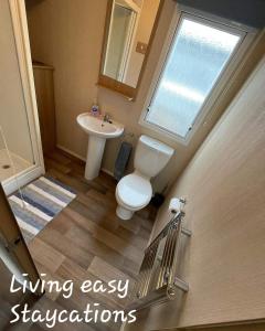 a bathroom with a toilet and a sink and a window at Living Easy Staycations at Tattershall Lakes in Tattershall