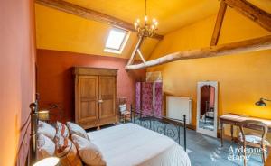 - une chambre avec un grand lit dans une pièce aux murs jaunes dans l'établissement Gîte de la Ferme de Seron - gîte de charme avec bain nordique, à Fernelmont