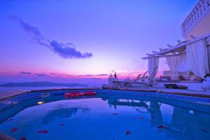 a swimming pool with a sunset in the background at Thea Apartments in Imerovigli