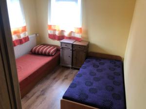 um pequeno quarto com 2 camas, uma secretária e uma janela em Apartament w domu przysłupowym 