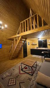 a living room with a staircase in a wooden ceiling at Eco cottage Kazbegi in Stepantsminda
