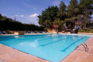 a large blue swimming pool with chairs and trees at Pousada e Camping Carrion in Itu