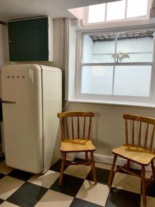 a kitchen with two chairs and a refrigerator and a window at Bats by the Sea at Number 23 in Scarborough