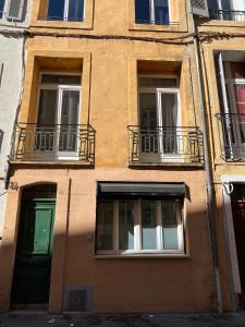 a building with three windows and a green door at Le Petit Patio in Aix-en-Provence