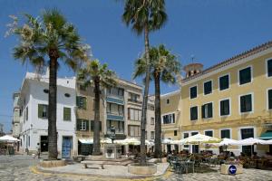 una calle de la ciudad con palmeras, mesas y sombrillas en Villa Marline by Villa Plus, en Cala'n Porter