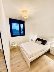 a white bedroom with a bed and a window at Acogedor y cómodo apartamento con piscina in Las Palmas de Gran Canaria