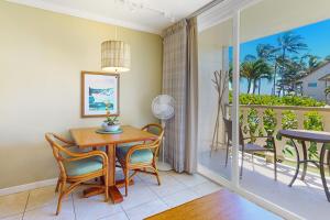 a dining room with a table and chairs and a balcony at Islander on the Beach 235 in Kapaa