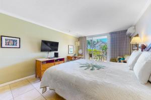 a bedroom with a large bed and a television at Islander on the Beach 235 in Kapaa