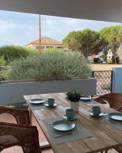 a wooden table with cups and saucers on a patio at Cabanas Acqua Golden in Cabanas de Tavira