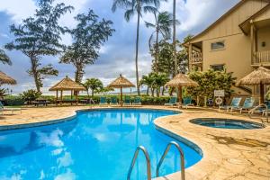 a pool with chairs and umbrellas at a resort at Islander on the Beach 353 in Kapaa