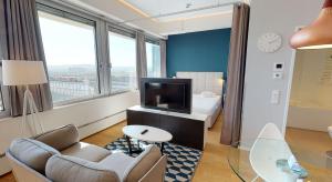 Habitación de hotel con TV, sofá y cama en Key Residences Vienna en Viena