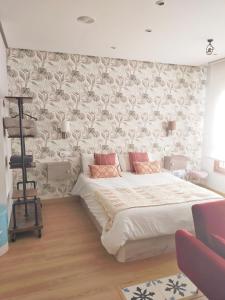 a bedroom with a large white bed with a floral wallpaper at Loft Oviedo in Oviedo