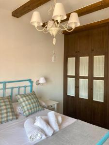 Un dormitorio con una cama con almohadas blancas y una lámpara de araña. en Casa rural Solanilla, en Solanilla