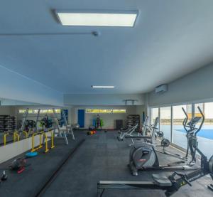 a gym with cardio equipment and a swimming pool at Cabanas Acqua Golden in Cabanas de Tavira