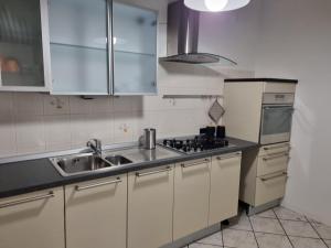 cocina con armarios blancos, fregadero y nevera en SWEET HOME, en Azzano San Paolo