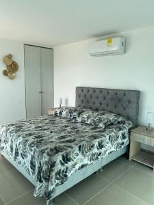 1 dormitorio con 1 cama con edredón blanco y negro en Cartagena, APARTAMENTO EN EDIFICIO CON SALIDA A LA PLAYA, en Cartagena de Indias