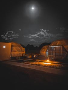 een groep tenten 's nachts met de maan in de lucht bij Rum Kingdom Camp in Wadi Rum