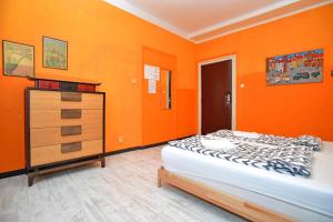 Schlafzimmer mit orangefarbenen Wänden, einem Bett und einer Kommode in der Unterkunft Prague Old Town Hostel in Prag