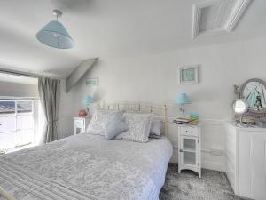 a white bedroom with a bed and two night stands at Watersplash Cottage in Lyme Regis