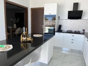 a kitchen with white cabinets and a black counter top at Villa Dar lynoute in Taguermess