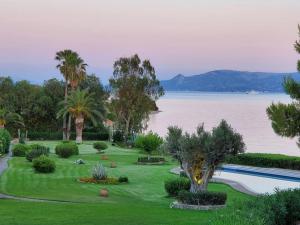 a garden with a swimming pool next to a body of water at Architect designed house with pool and private beach in Eretria
