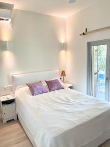 a bedroom with a white bed with two purple pillows at Architect designed house with pool and private beach in Eretria