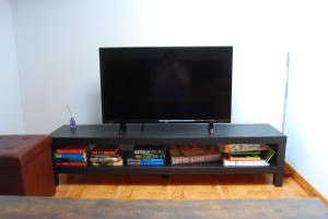 a black entertainment center with a tv and books at Casa Rural Puerta del Gamoniteiru in Pola de Lena