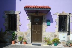 une maison violette avec une porte marron et un toit rouge dans l'établissement Casa Rural Puerta del Gamoniteiru, à Pola de Lena